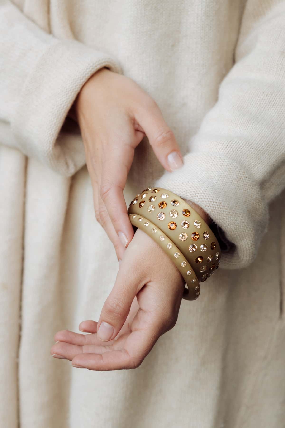 Hand mit Coloristers Armreifen mit Kristallen in Beige. Hands with Coloristers Bangles with crystals in beige.