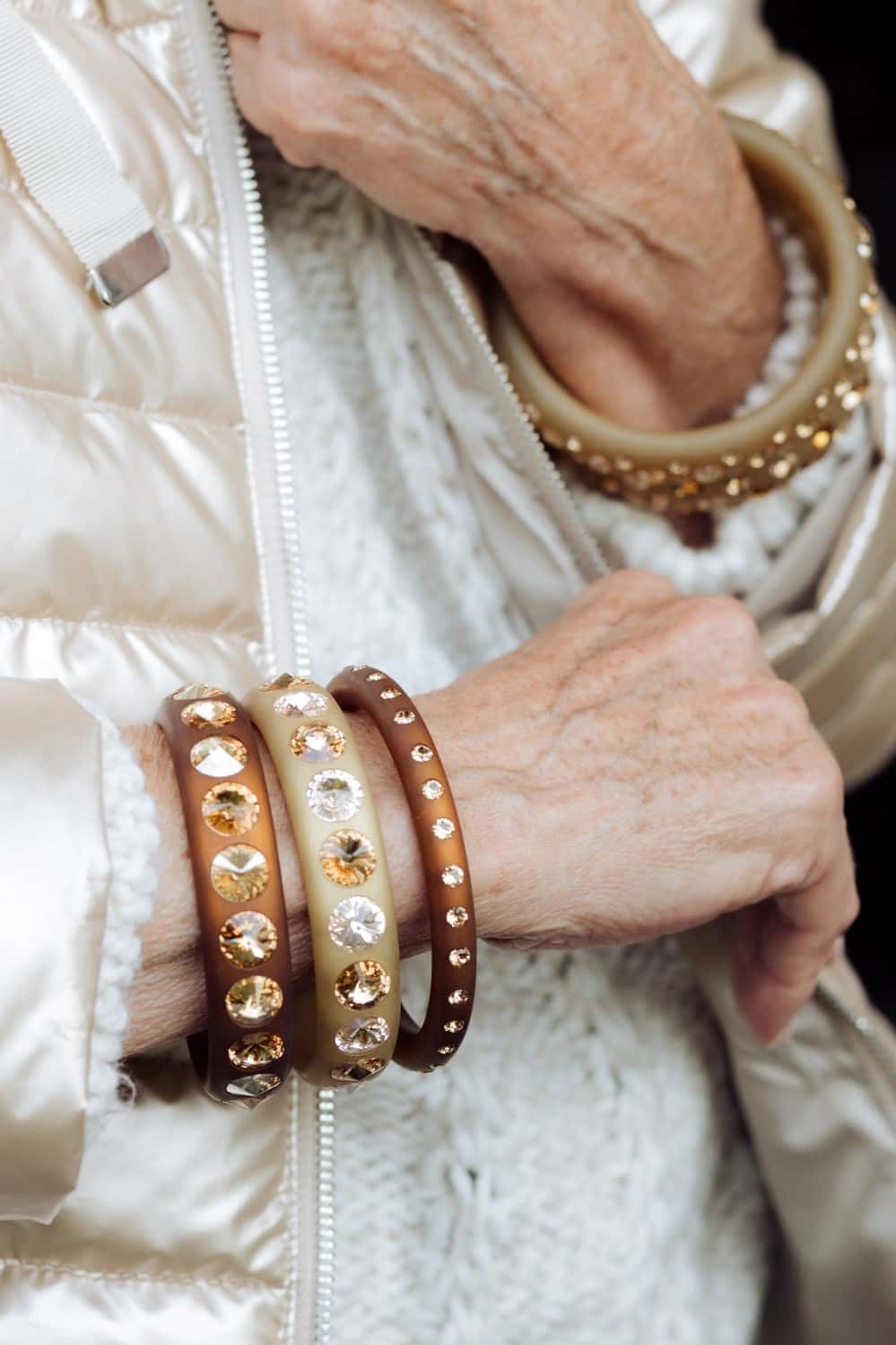 Hand mit Coloristers Armreifen mit Kristallen in Beige und Braun. Hand with brown and beige Coloristers bangles with crystals.