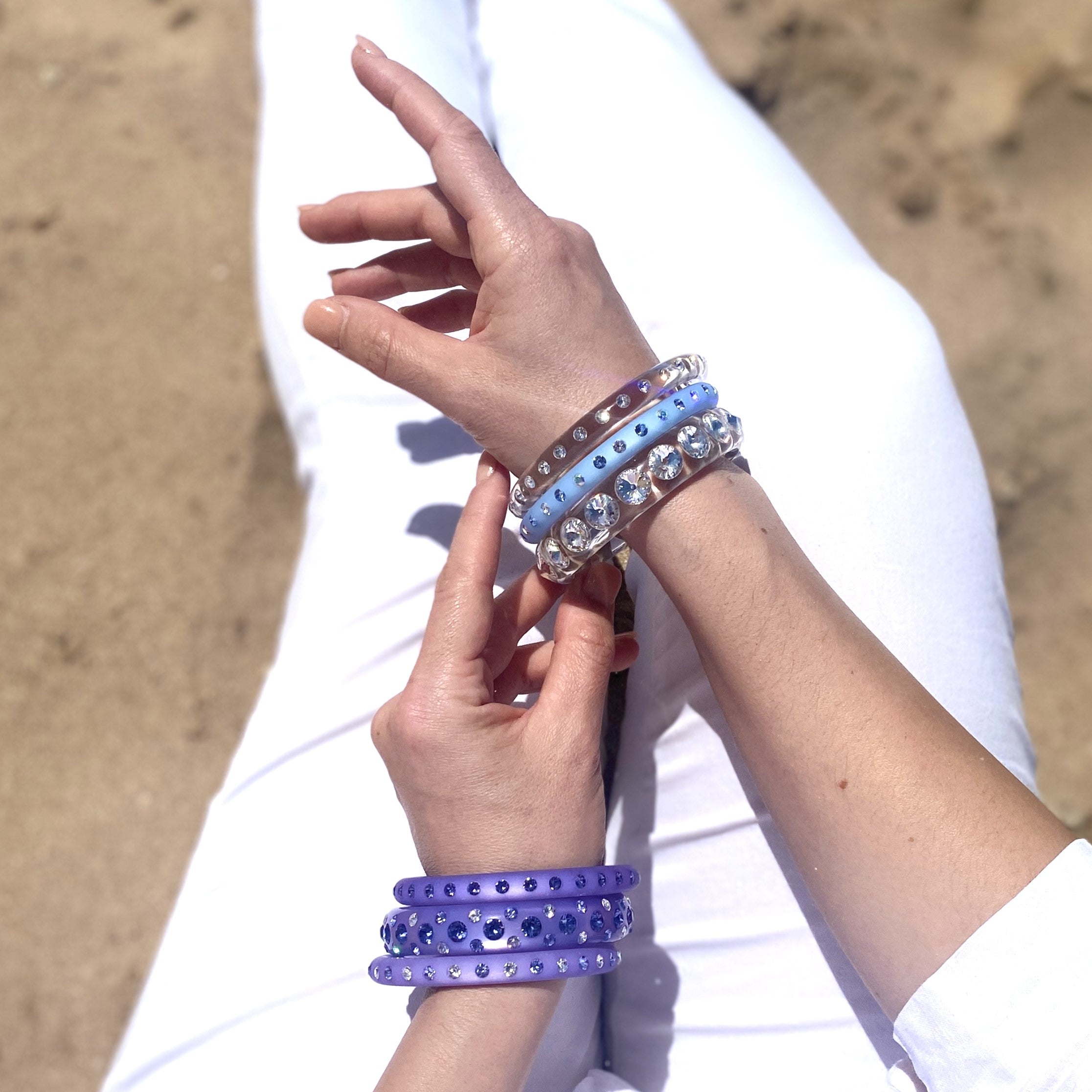 Hand mit bunten Coloristers Armreifen mit Kristallen. Hand with colourful Coloristers bangles with crystals. 