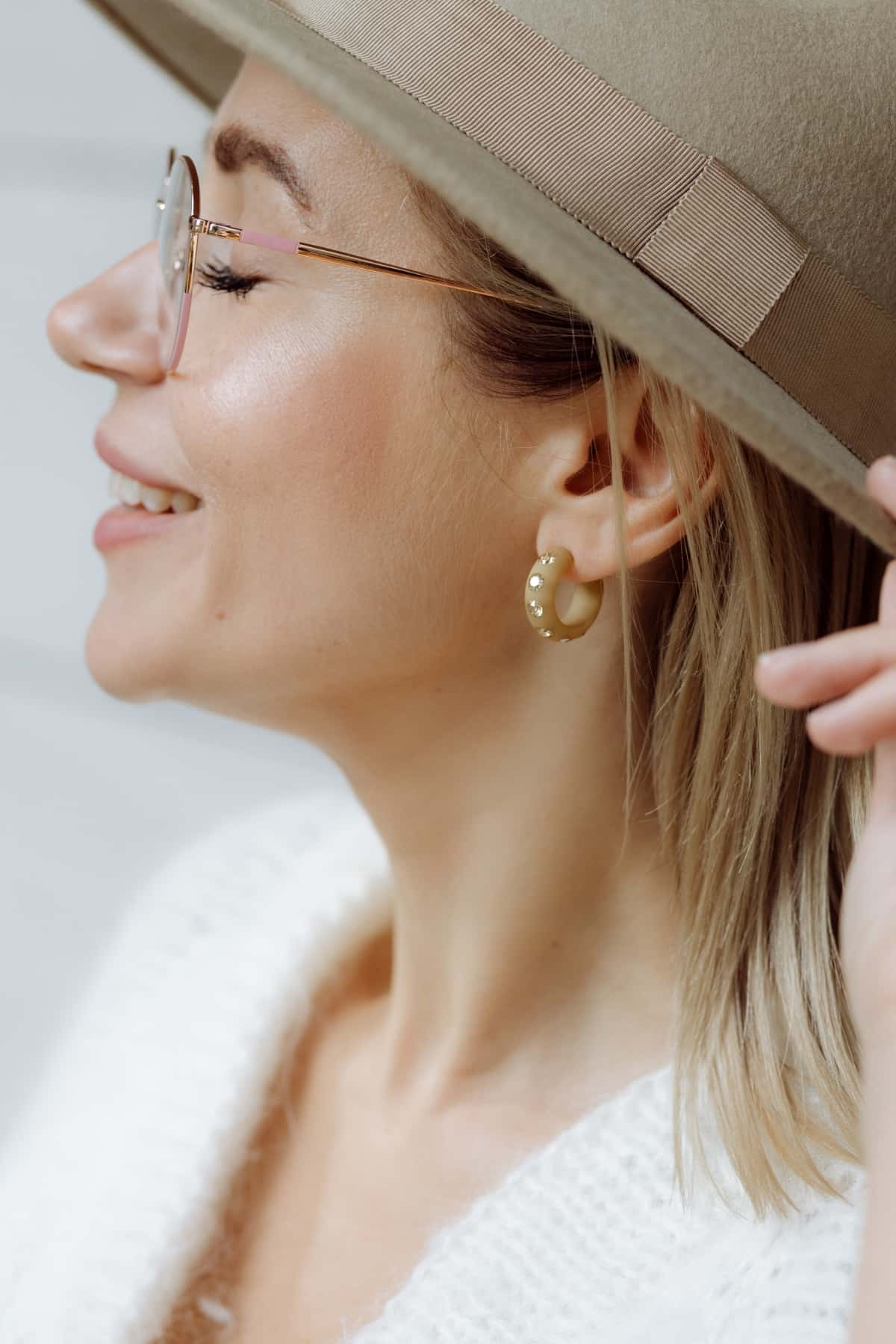 Frau mit Coloristers Ohrringen Creolen mit Kristallen in Beige. Woman with Coloristers earrings creoles with crystals in beige.